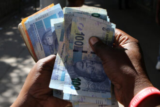 A street money changer counts South African Rands in Harare.